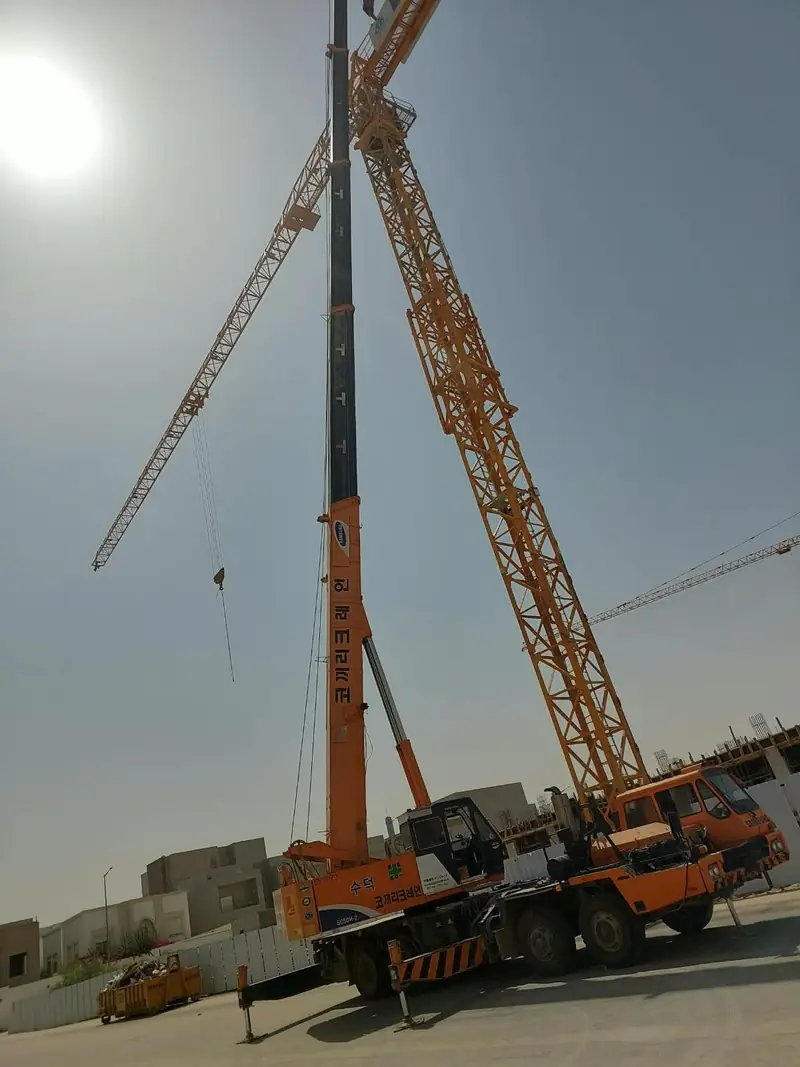 رافعة كرين بذراع تلسكوبي ممتد داخل موقع إنشاءات بجانب رافعات برجية